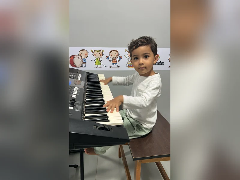 Criança em aula de música tocando teclado na Escola de Música Holanda Premium, em Goiânia