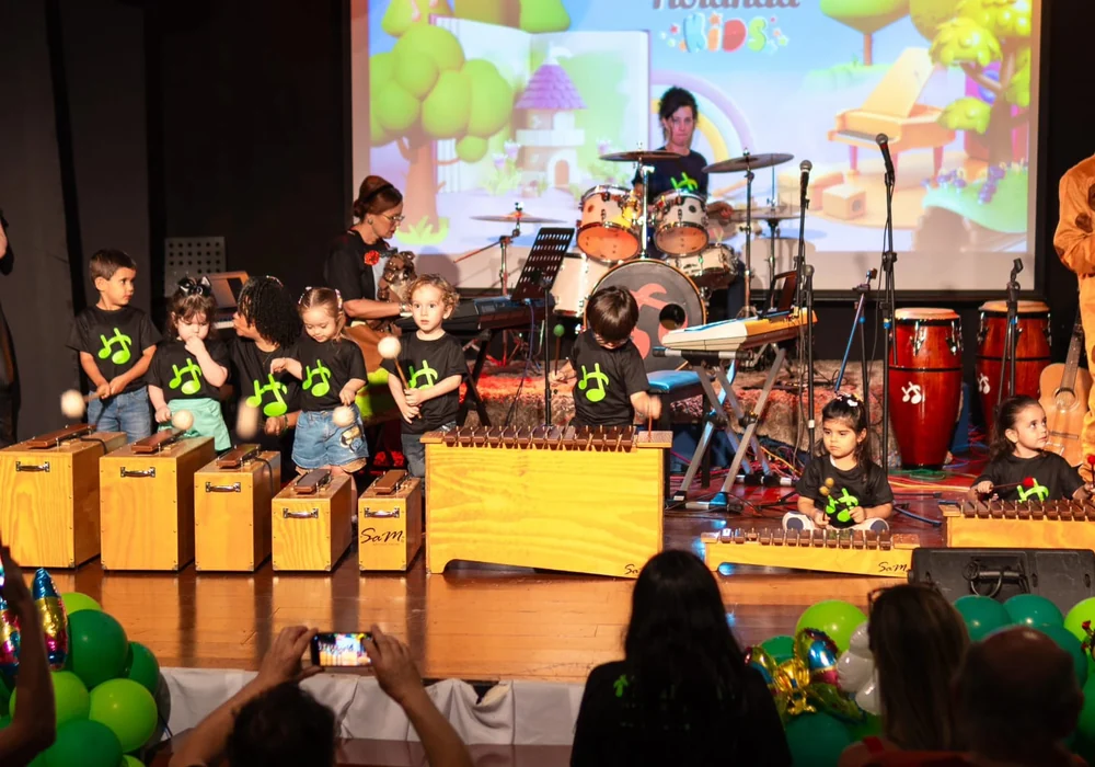 Turma de musicalização infantil da Holanda Premium tocando instrumentos no palco em Goiânia