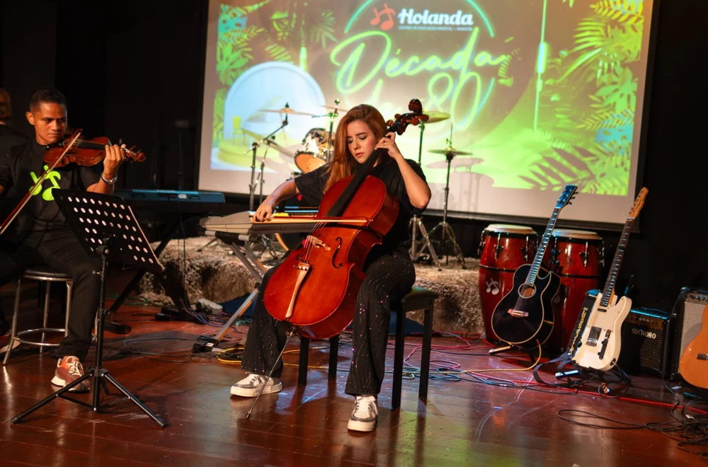 Alunos tocando violoncelo e violino no palco em recital da Escola de Música Holanda Premium, em Goiânia
