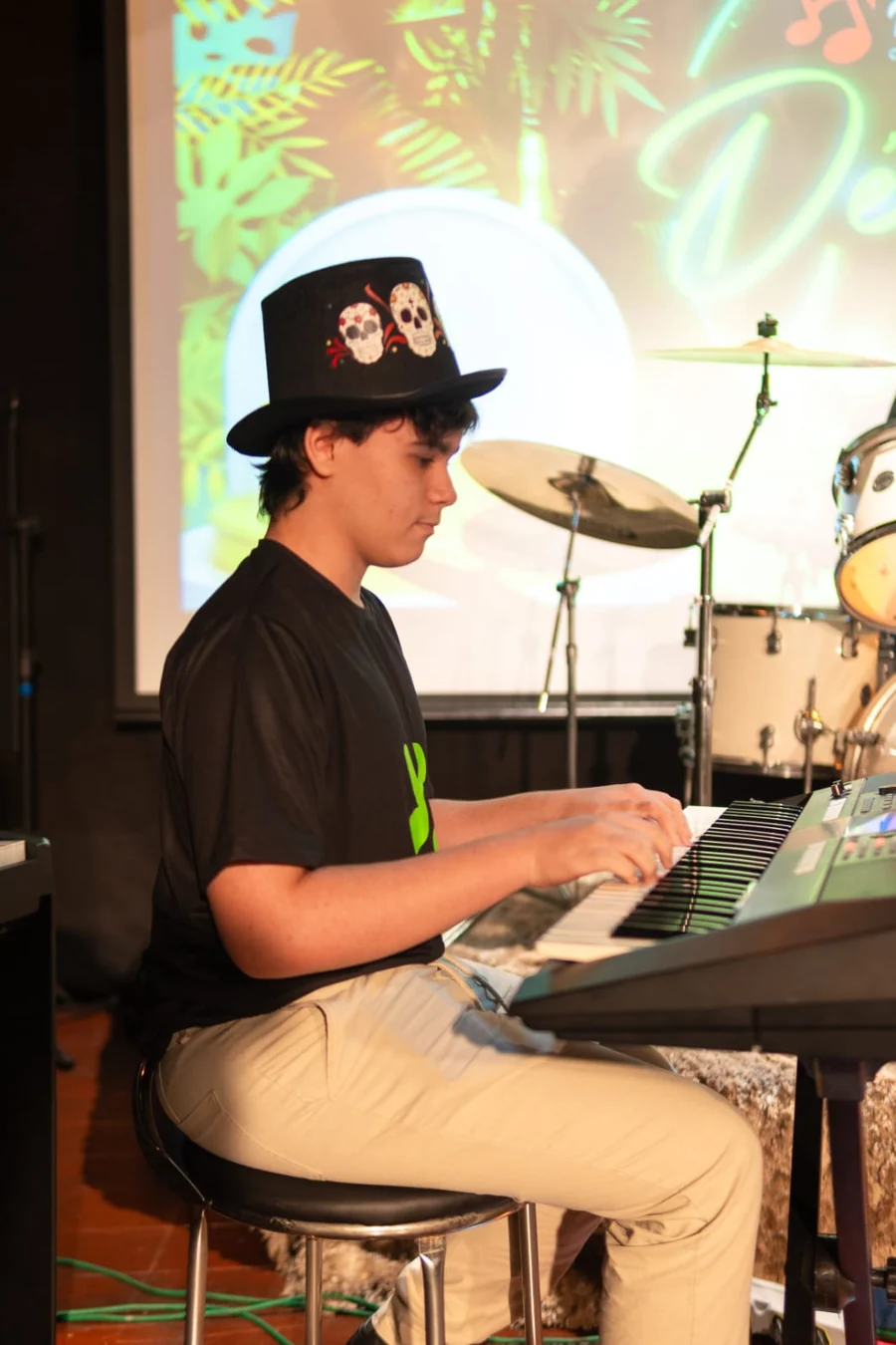 Aluno tocando teclado no palco durante recital da Holanda Premium em Goiânia