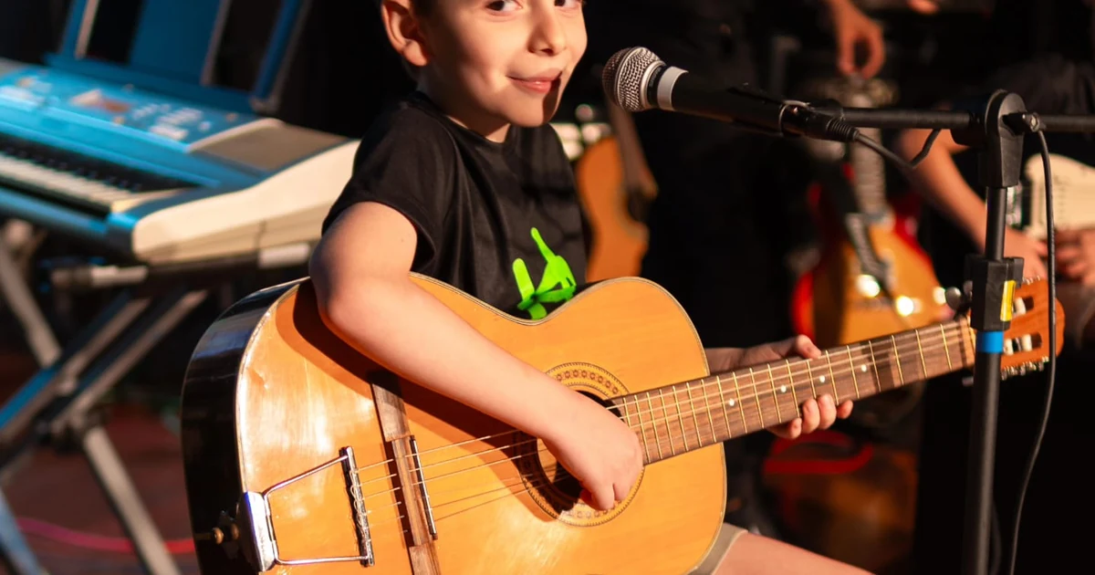 Aluno tocando violão no palco durante recital da Escola de Música Holanda Premium em Goiânia